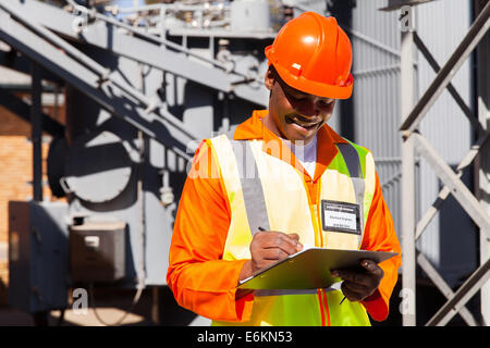 glücklich afrikanische Elektriker schreiben über Zwischenablage in elektrische Unterstation Stockfoto