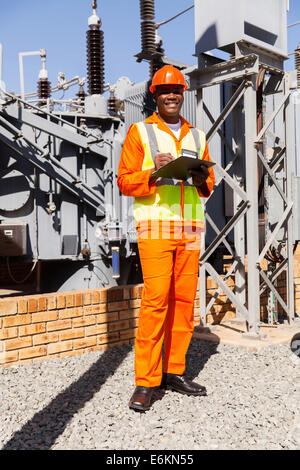 glücklich Afro amerikanischer Elektroingenieur mit Zwischenablage im Kraftwerk Stockfoto