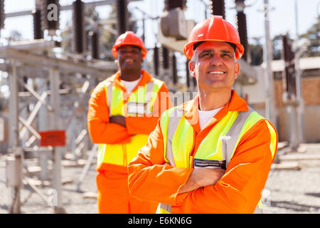 gut aussehend mittleren gealterten elektrischen Arbeiter nachschlagen mit Kollegen auf Hintergrund Stockfoto