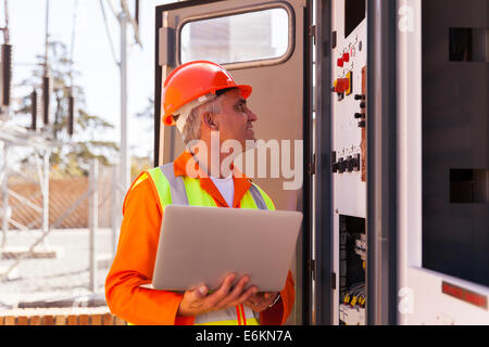 erfahrener senior Elektriker arbeitet an einem Transformator im Umspannwerk Stockfoto