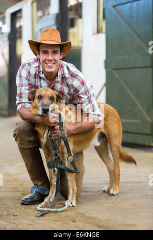 Happy Horse Farm Besitzer und seinem Hund in Ställen Stockfoto