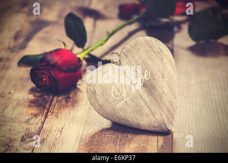 Vintage Bild des Herzens auf einem hölzernen Hintergrund mit roten Rose. Valentinstag-Symbol. Stockfoto