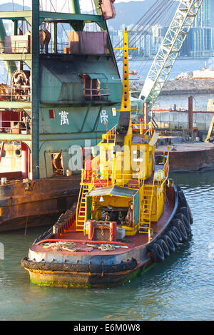 Schlepper bewegt sich ein Derrick Barge In der Causeway Bay Typhoon Shelter, Hong Kong. Stockfoto