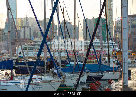 Kreuzfahrtschiff Dämpfen durch den Victoria Harbour. Durch den Mast der Boote gesehen günstig in der Causeway Bay Typhoon Shelter, Hong Kong Skyline hinter sich. Stockfoto