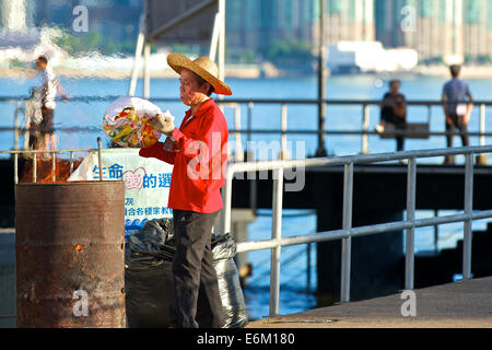 Chinesische Reiniger in einen Strohhut brennen Abfälle auf Pier North Point, Hong Kong. Stockfoto