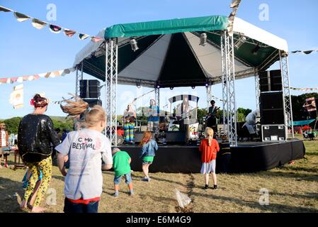 Kinder tanzen zur Isle Of Wight-Reggae-Band The Ohmz am Camp Bestival 2014 bei Lulworth Castle Stockfoto