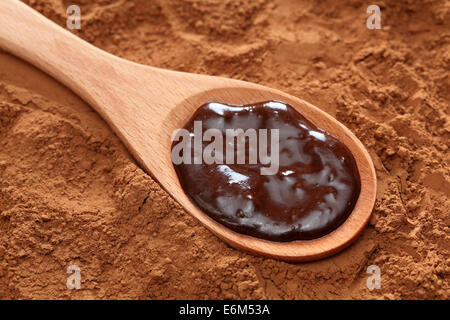 Schokolade in einem hölzernen Löffel Kakaopulver Hintergrund. Closeup. Stockfoto