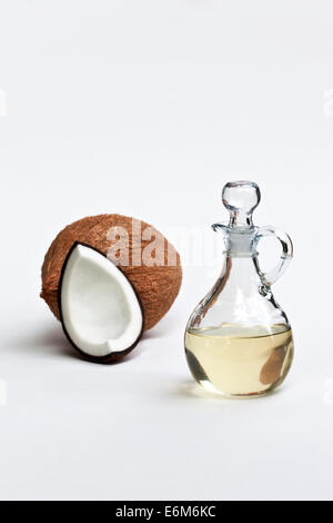 Kokosöl in Glaskaraffe, geviertelt & ganze Kokosnuss. Stockfoto