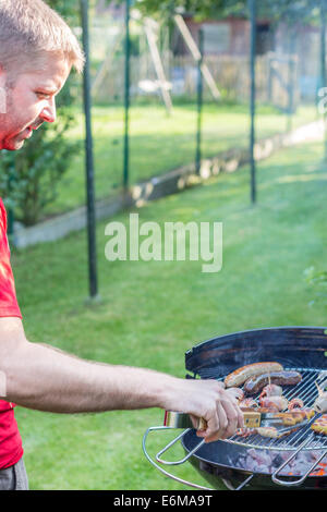 Mann, Kochen von Fleisch auf dem Grill - links Stockfoto