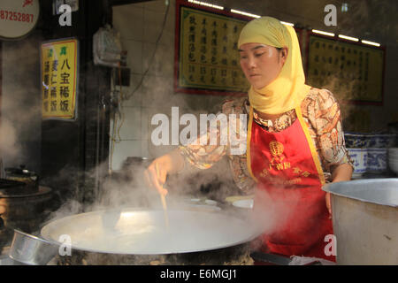 Einen weiblichen muslimischen Hui verkauft Lebensmittel in der muslimischen Viertel Nachbarschaft von Xi ' an, China. Stockfoto