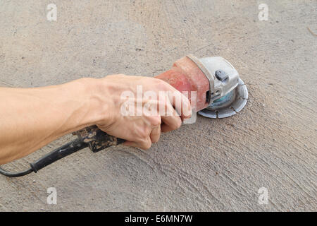 Hand mit Schleifwerkzeug auf konkrete Hintergrund Stockfoto