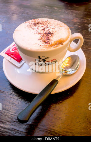 Cappuccino mit einem Zuckerbeutel und einem Löffel, Italien Stockfoto