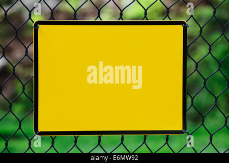 Leere gelbe Info-Platte hing an einem Drahtzaun Stockfoto