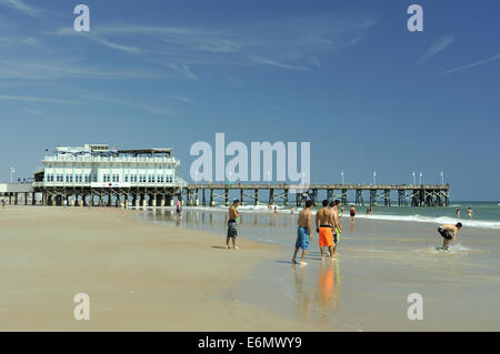 Gruppe von Jungs im Teenageralter spielen am Strand, mit Daytona Beach Pier im Hintergrund. Daytona Beach, Florida, USA Stockfoto