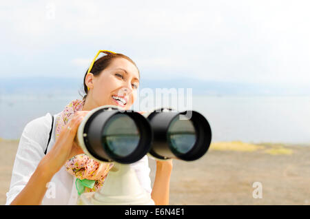 Lächelnde Frau Blick durch das Fernglas oder Teleskop Stockfoto