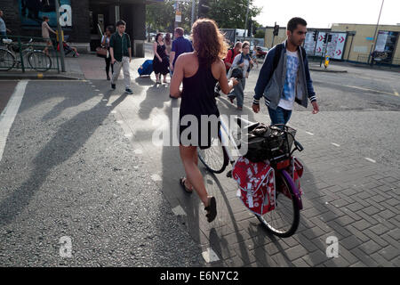 Frau mit Vintage Fahrrad im Sommer aus gesehen hinter der Überquerung der Straße in der Nähe von Blackhorse Road U-Bahnstation Walthamstow London E 17 UK KATHY DEWITT Stockfoto