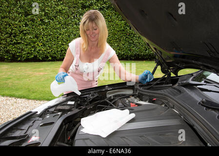 Frau Nachfüllen Windschutzscheibe Unterlegscheibe Flasche im Motorraum ihres Autos Stockfoto