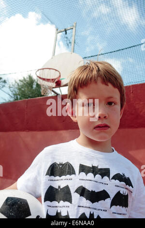 Portrait eines fünfjährigen Jungen mit einem Fußball in einen Mehrzweck-Sportplatz Stockfoto