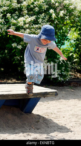 Ein zwei Jahre alter Junge, springen von einer Parkbank Stockfoto