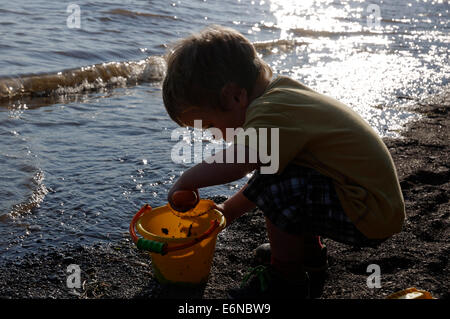 Ein Junge spielt mit einem Eimer und Spaten am Strand Stockfoto