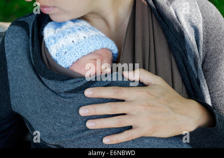 Ein neugeborenes Baby schläft in einem Tragetuch wickeln statt von der Mutter Stockfoto