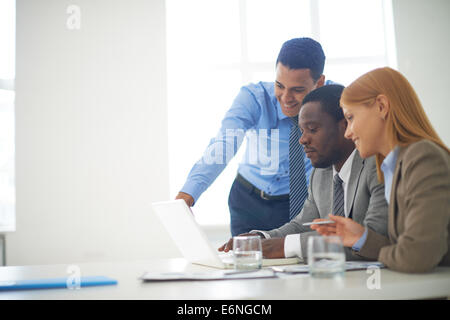Gruppe von zuversichtlich Geschäftspartner arbeiten mit Laptop im Büro Stockfoto