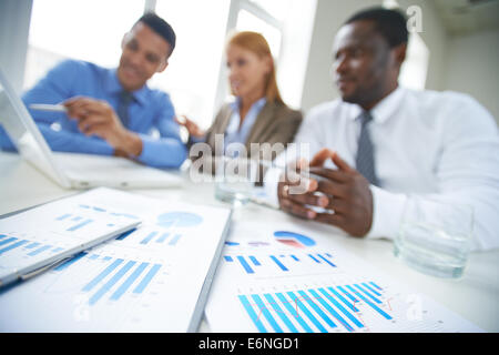 Ablagen und Stift am Arbeitsplatz mit Business-Team im Hintergrund Stockfoto