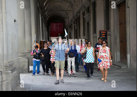 Männliche Reiseführer mit Fähnchen zeigen Touristen rund um den gewölbten Parkwege in Florenz, Italien. Stockfoto