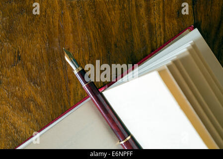 Nahaufnahme der Füllfederhalter auf ein rotes Buch auf einem Holztisch. Stockfoto