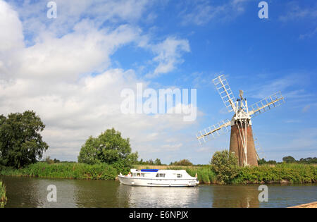 Ein Kreuzer auf den Norfolk Broads vorbei Turf Moor-Entwässerung-Mühle in der Nähe wie Hill, Ludham, Norfolk, England, Vereinigtes Königreich. Stockfoto