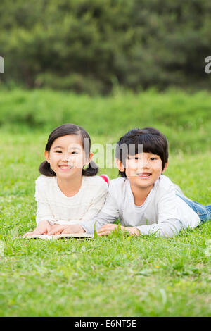 Jungen und Mädchen, die vorne auf der Wiese liegend Stockfoto