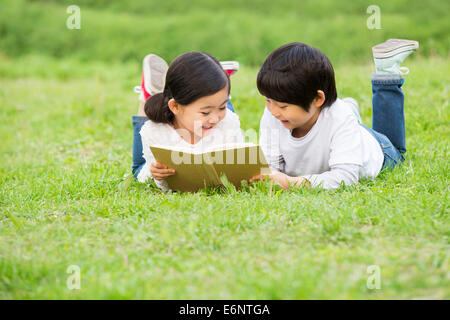 Jungen und Mädchen auf dem Rasen lesen Stockfoto