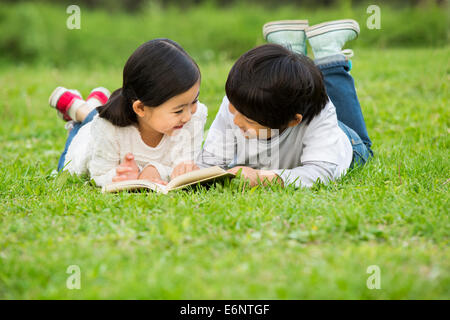 Jungen und Mädchen auf dem Rasen lesen Stockfoto