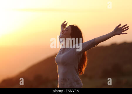 Hintergrundbeleuchtung einer Frau am Sonnenuntergang frische Atemluft Arme Stockfoto