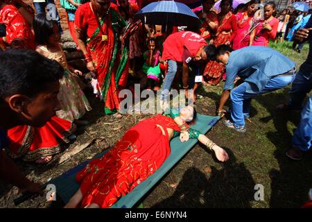 Kathmandu, Nepal. 28. August 2014. Freiwillige kümmern sich um eine Hindu-Frau, die in einer Warteschlange auf Pashupatinath Tempel während der Teej Festival in Kathmandu, Nepal, 28. August 2014 in Ohnmacht gefallen. Während des Festivals verheiratete Frauen Fasten und beten für gute Gesundheit und langes Leben ihrer Ehemänner und unverheiratete Frauen beten für gesunde und schöne Männer zu heiraten. Bildnachweis: Sunil Sharma/Xinhua/Alamy Live-Nachrichten Stockfoto