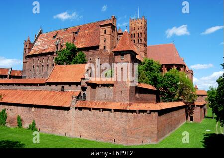 MALBORK, Polen: Den trockenen Graben, jetzt gefüllt mit Rasenflächen, äußere Wehrmauern und massiven Gebäuden auf Schloss Marienburg Stockfoto