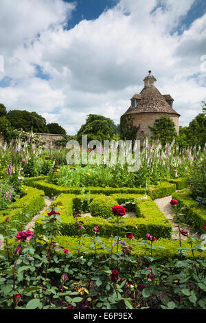 Die Box-Hedge-Parterre mit Sommerblumen und c.1685 Taubenschlag im ummauerten Garten der Rousham House, Oxfordshire, England Stockfoto