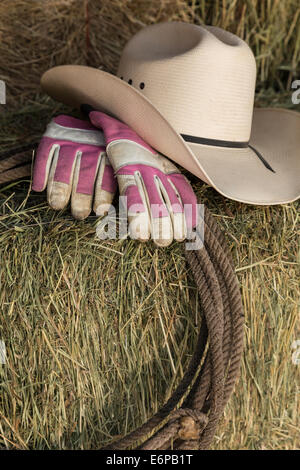 Stillleben-Cowboy-Hut, Lasso und Arbeitshandschuhe auf einen Ballen Heu, Montana, USA Stockfoto