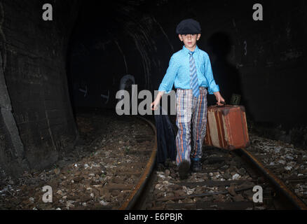 Kind zu Fuß mit Vintage Siutcase Eisenbahn unterwegs. Stockfoto