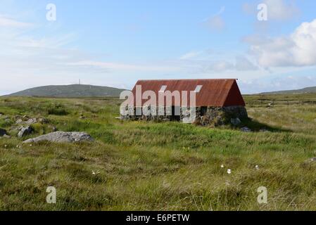 Eine kleine Alm mit rostenden Dach auf dem Torf Mauren von den äußeren Hebriden, Schottland Stockfoto