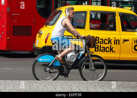 Ein Radfahrer tragen von Kopfhörern und Radfahren im Verkehr in London Stockfoto