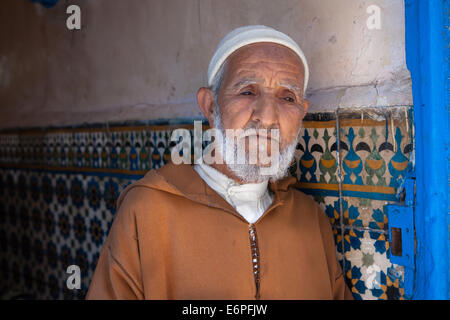 Alten muslimischen Mann, trägt eine traditionelle Djellaba, stehend in einem Hauseingang in der alten Medina von Essaouira, Marokko. -Modell veröffentlicht. Stockfoto