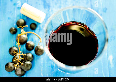 Glas Rotwein auf alten Balken. In der Nähe der Weinkorken und Weintraube. Stockfoto