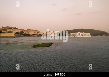 Blick vom See Pichola bei Sonnenuntergang in Richtung Lake Palace Hotel und City Palace in Udaipur, Rajastan, Indien Stockfoto