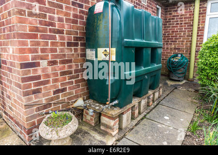 Eine inländische Kunststoff Öltank, stehend auf einer Plattform über dem Boden, neben der Unterkunft ein, in einem Garten in Northborough, Cambridgeshire, England, UK. Stockfoto