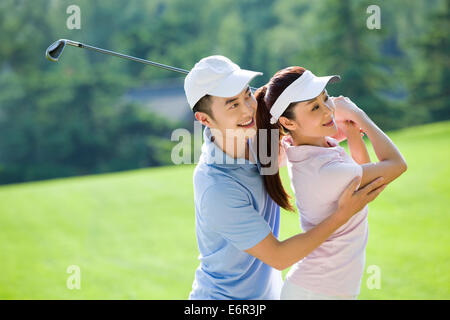 Junger Mann seine Freundin beizubringen, wie man Golf spielen Stockfoto