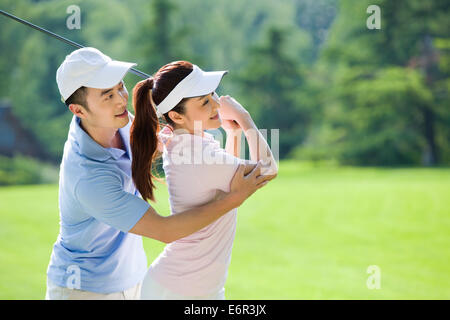 Junger Mann seine Freundin beizubringen, wie man Golf spielen Stockfoto