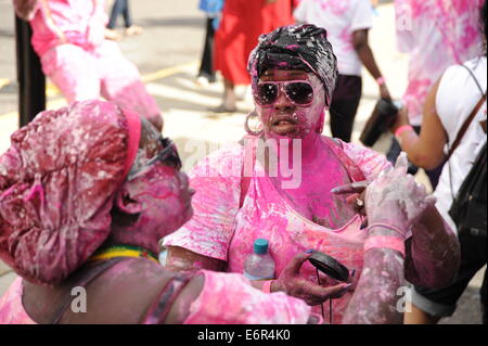 zwei junge schwarze Frauen bedeckt in rosa und Weiss Lack Nottinghill Carnival London am Familientag Stockfoto