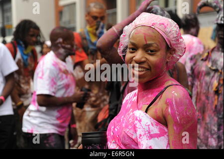 Young Black Women in Notting Hill Carnival in rosa Farbe in die Kamera Lächeln bedeckt Stockfoto
