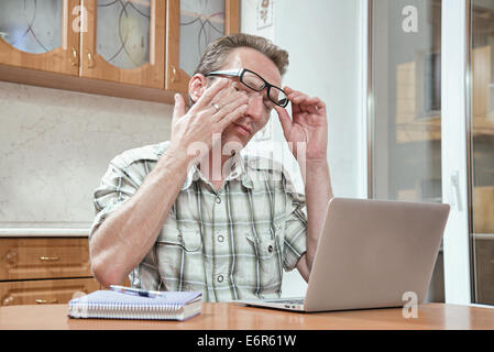 müde Schüler reiben seinen Augen arbeiten spät in die Nacht in der Küche bei seinen Prüfungen Stockfoto